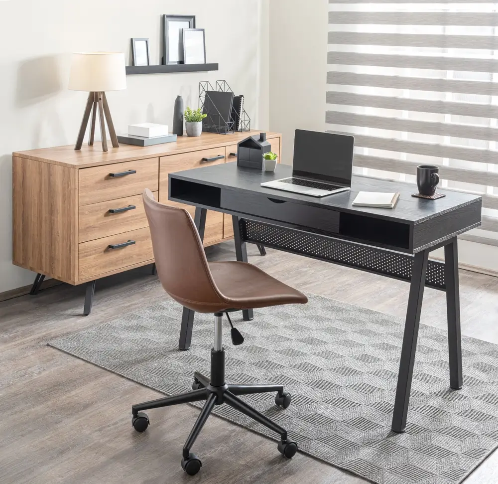Bureau à domicile moderne et rationalisé avec un bureau noir perforé, chaise de bureau en cuir Tan d'inspiration du milieu du siècle, Buffet en bois assorti, tapis géométrique et un ensemble d'étagères flottantes au-dessus de l'affichage.