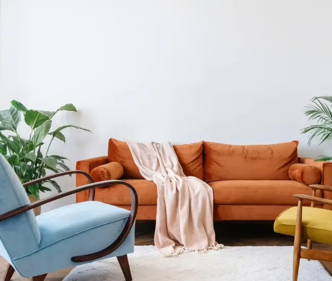 Concept d'aménagement intérieur dans le style des années 80. Vue de face d'un salon élégant avec un canapé orange vintage et des fauteuils bleus et jaunes.