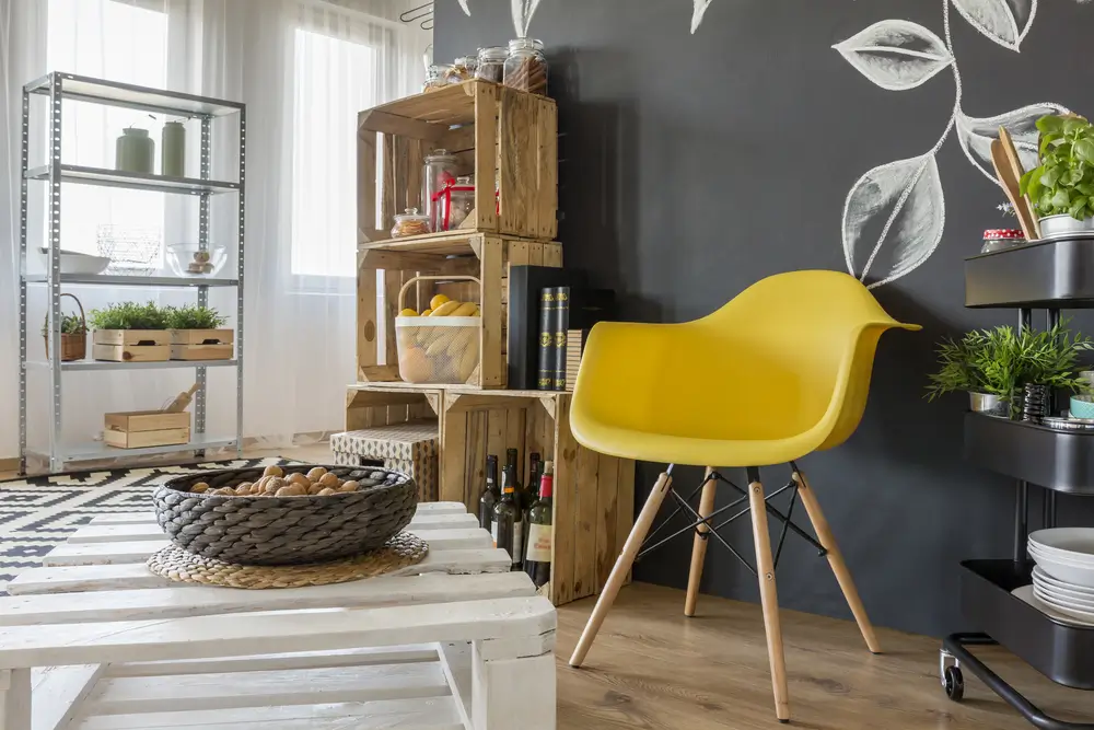 Chambre avec mobilier en palettes, tableau et chaise jaune.