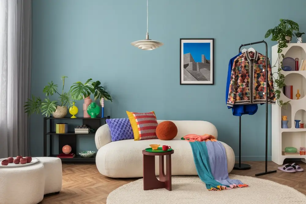 Intérieur moderne et coloré du salon avec canapé bouclé design, affiche maquette, étagère, plantes, décorations et objets personnels.