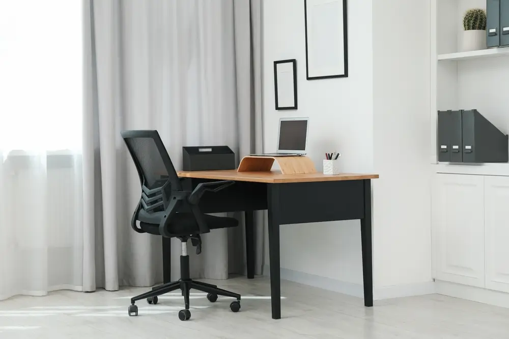 Chaise noire, ordinateur portable et bureau au bureau.